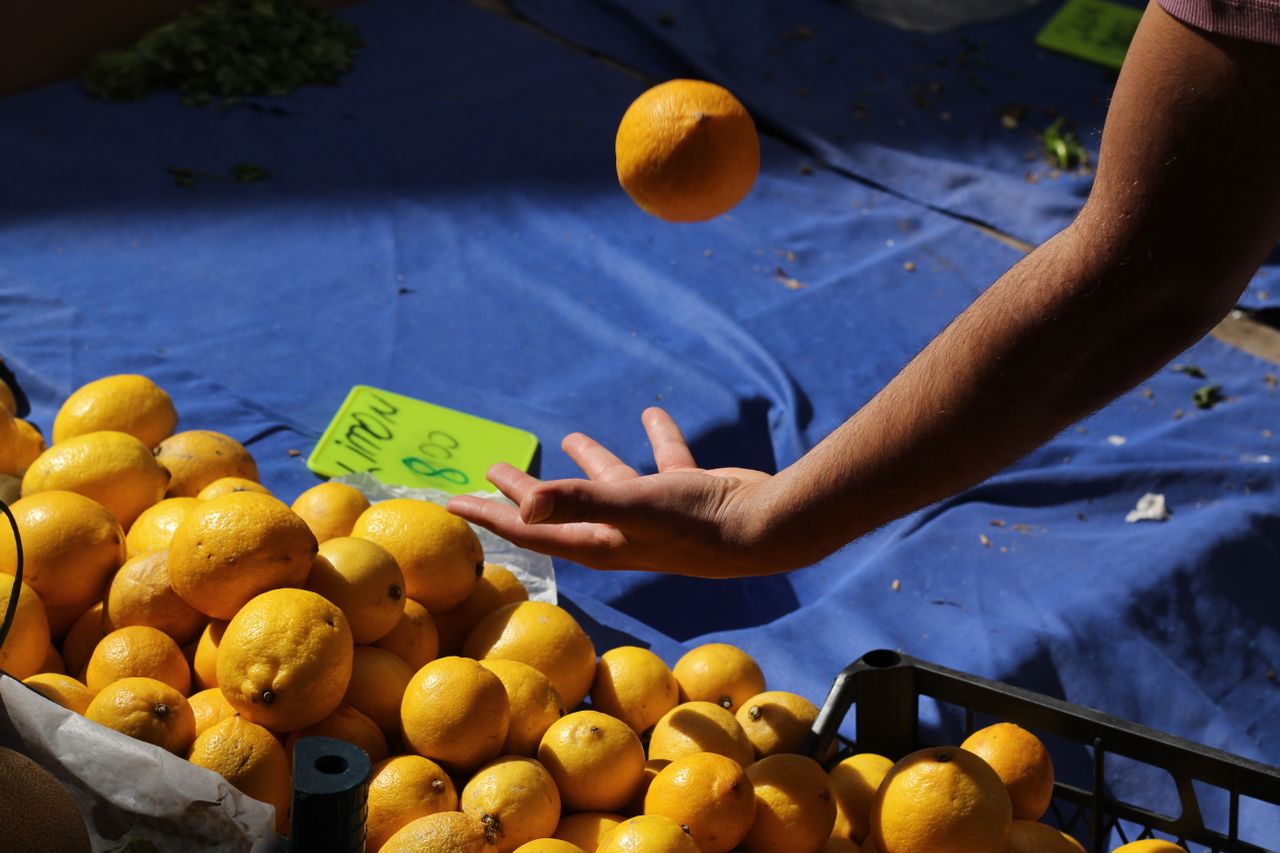 A pile of lemons with a person throwing one up in the air